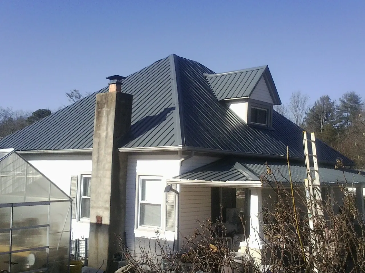 Dark blue standing seam metal roof on a white farmhouse with dormer — Slate & Tile Roof Repair by Roofing Brothers in Providence Forge