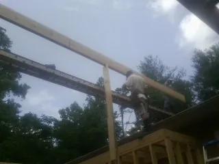Carpenter setting a ridge beam over a new addition frame — Ice Dam Removal by Roofing Brothers in Providence Forge