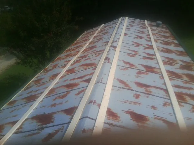Rusted metal roof panels with new wood purlins before replacement — Storm Damage Roof Repair in Providence Forge by Roofing Brothers