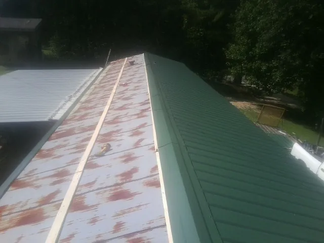 Old rusted panels beside newly installed green metal roofing — Wind Damage Roof Repair by Roofing Brothers in Providence Forge