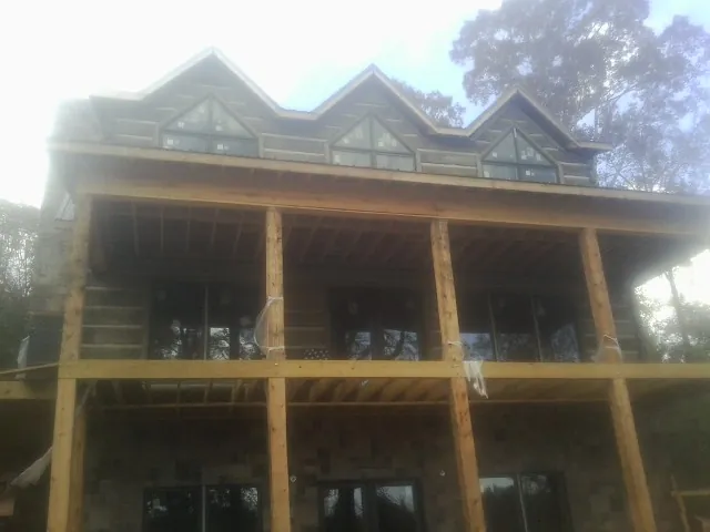 Dormers and porch framing on a large log home under construction — Roof Coating work by our crew in Providence Forge