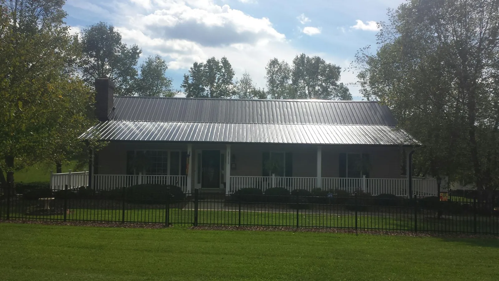 Gray metal roof on a brick ranch with a full width front porch — Gutter Guard Installation work by our crew in Providence Forge